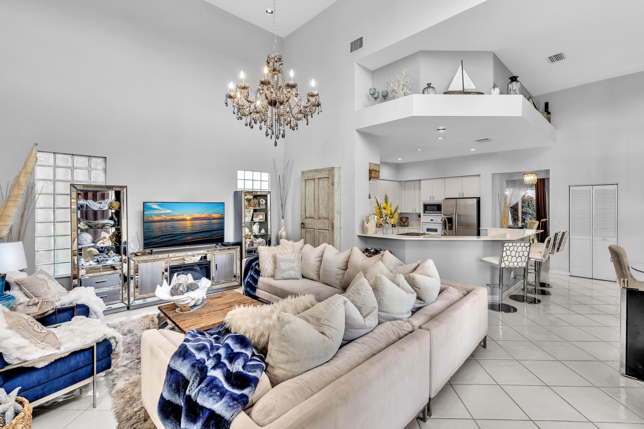 6230 Northwest 23rd Street Boca Raton, FL 33434 - Photo 31 of 90 a living room with furniture a chandelier and a flat screen tv