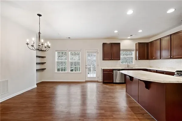 a large kitchen with stainless steel appliances granite countertop a sink dishwasher a stove and a large oven with wooden floor