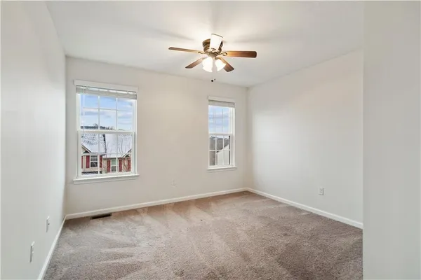 an empty room with windows and fan