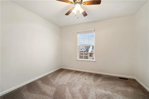an empty room with a chandelier fan and windows