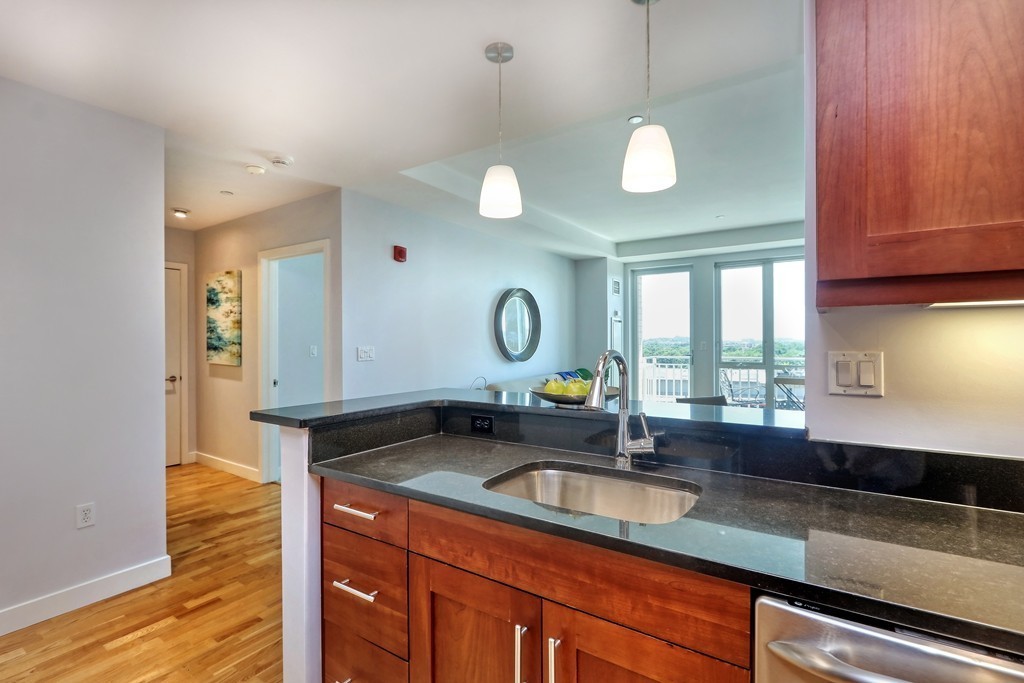 100 Station Landing, Unit 906 Medford, MA 02155 - Photo 5 of 28 a kitchen with granite countertop a sink a stove and cabinets