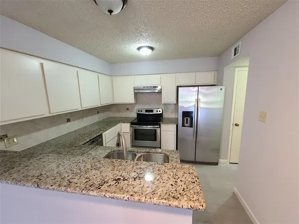 a kitchen with a refrigerator sink and cabinets