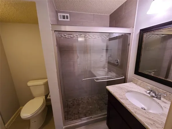 a bathroom with a granite countertop sink toilet and shower
