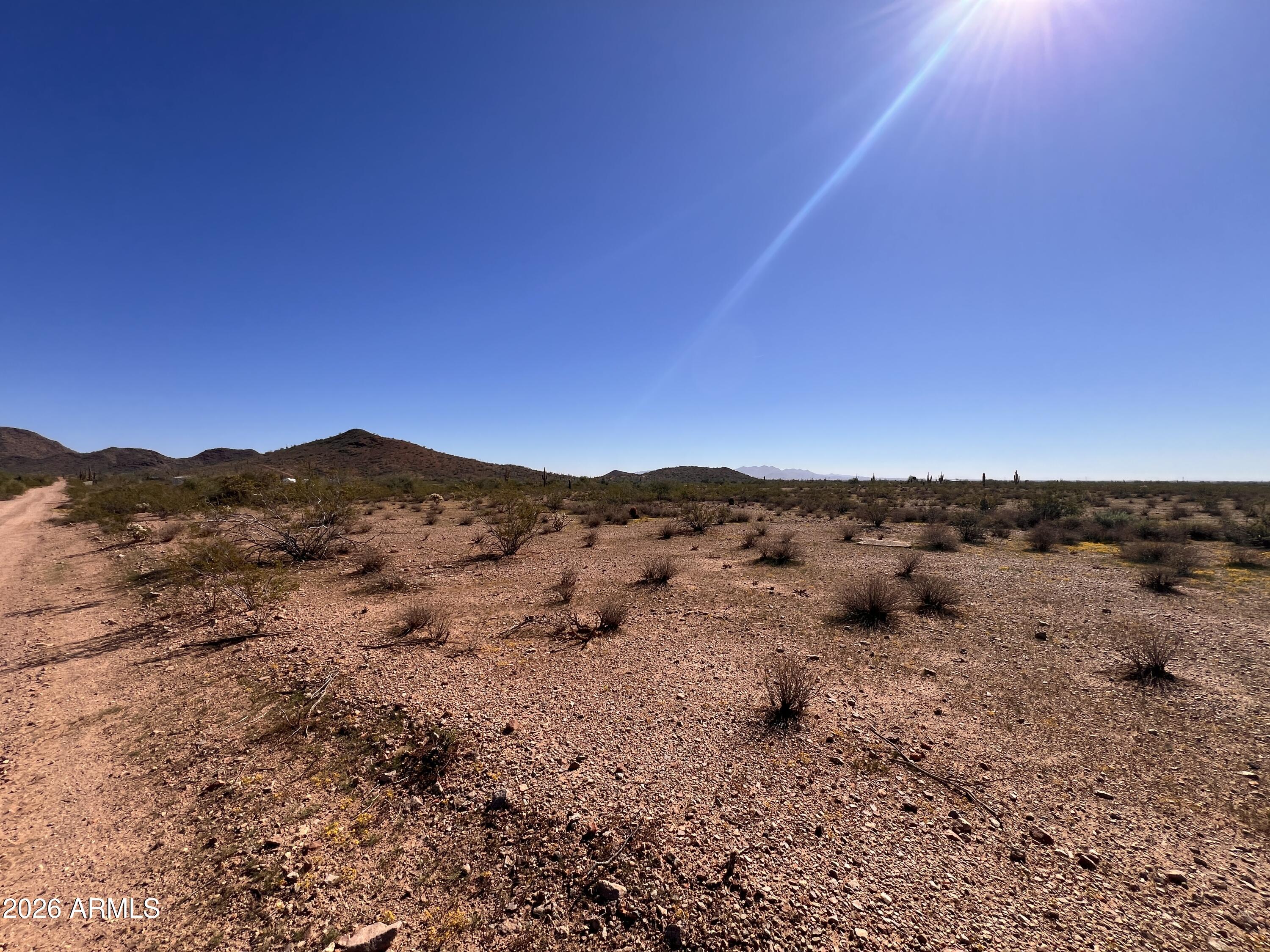 31-xxx West Carlise Road, Unit 105 Wittmann, AZ 85361 - Photo 4 of 9 a view of a dry yard with mountains in the background