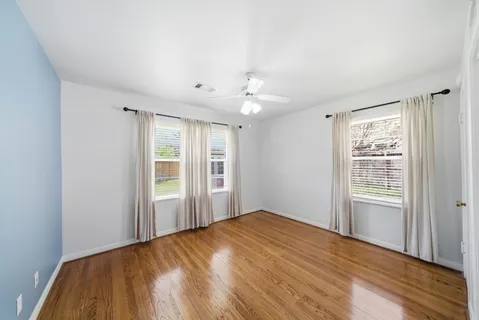 a view of empty room with wooden floor and fan