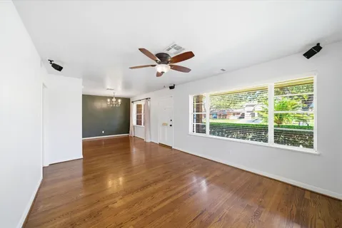 a view of an empty room with a window and wooden floor