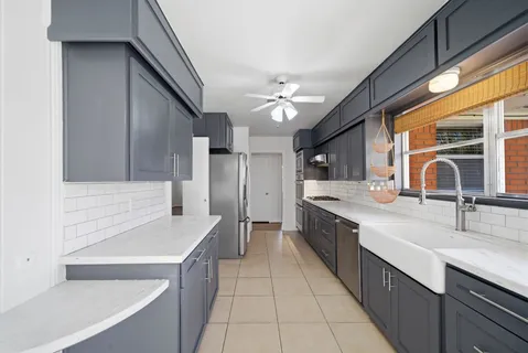 a large kitchen with a sink and dishwasher a stove top oven with wooden floor