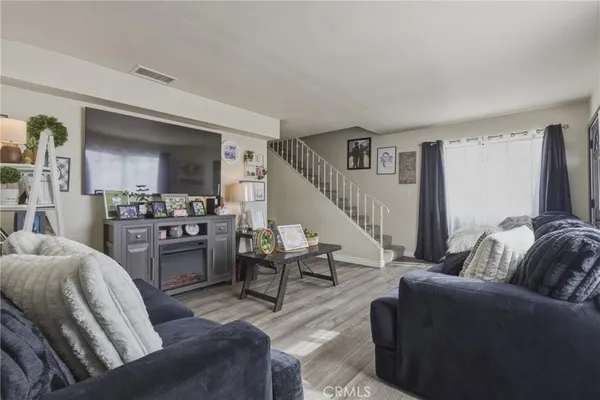 a living room with furniture kitchen view and a wooden floor