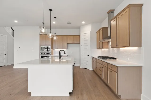 a large kitchen with stainless steel appliances kitchen island a large counter top and wooden floors