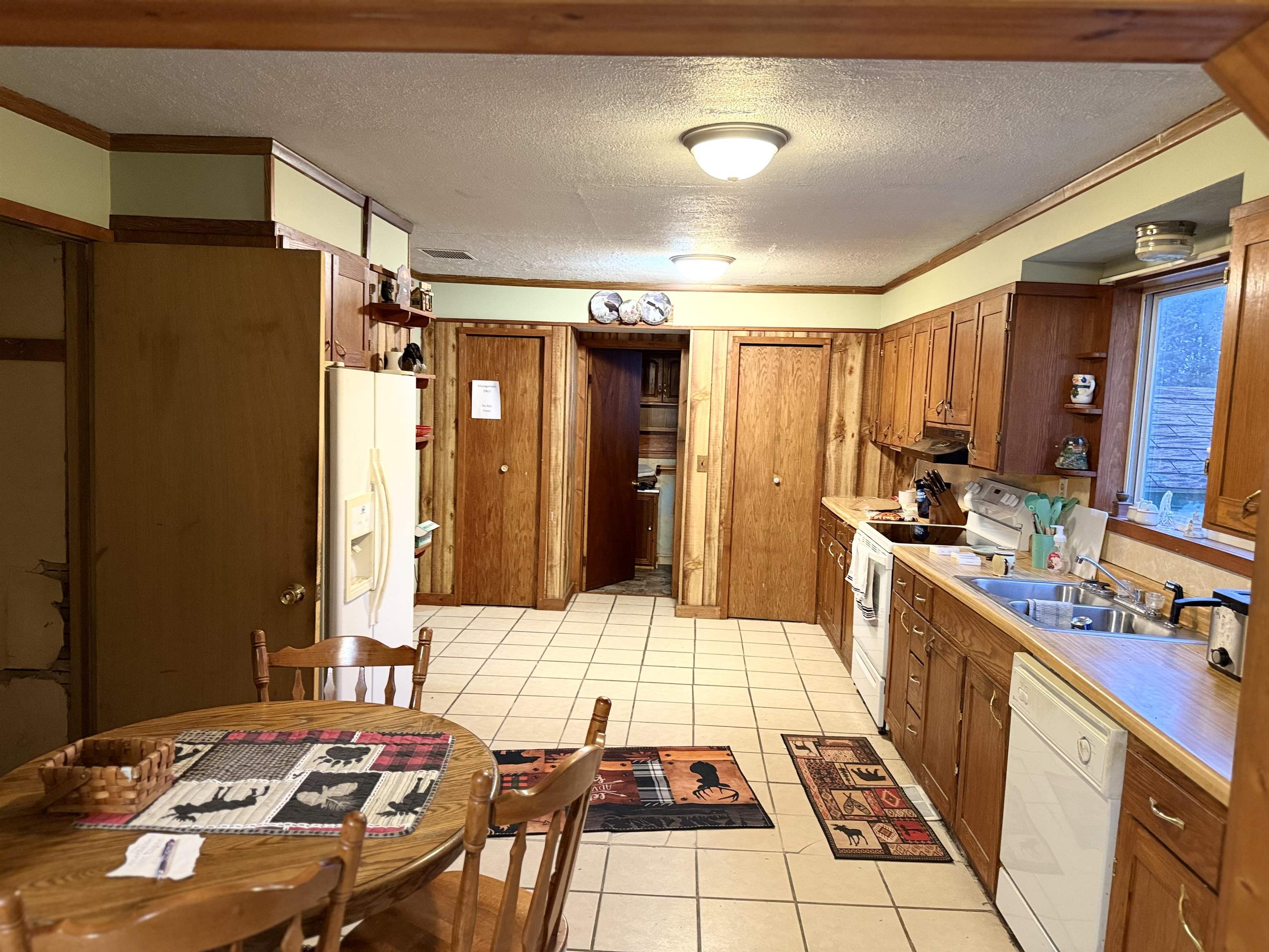 150 West 2nd Street Glidden, WI 54527 - Photo 12 of 32 Kitchen with brown cabinets, a textured ceiling, light countertops, light tile patterned floors, and white appliances