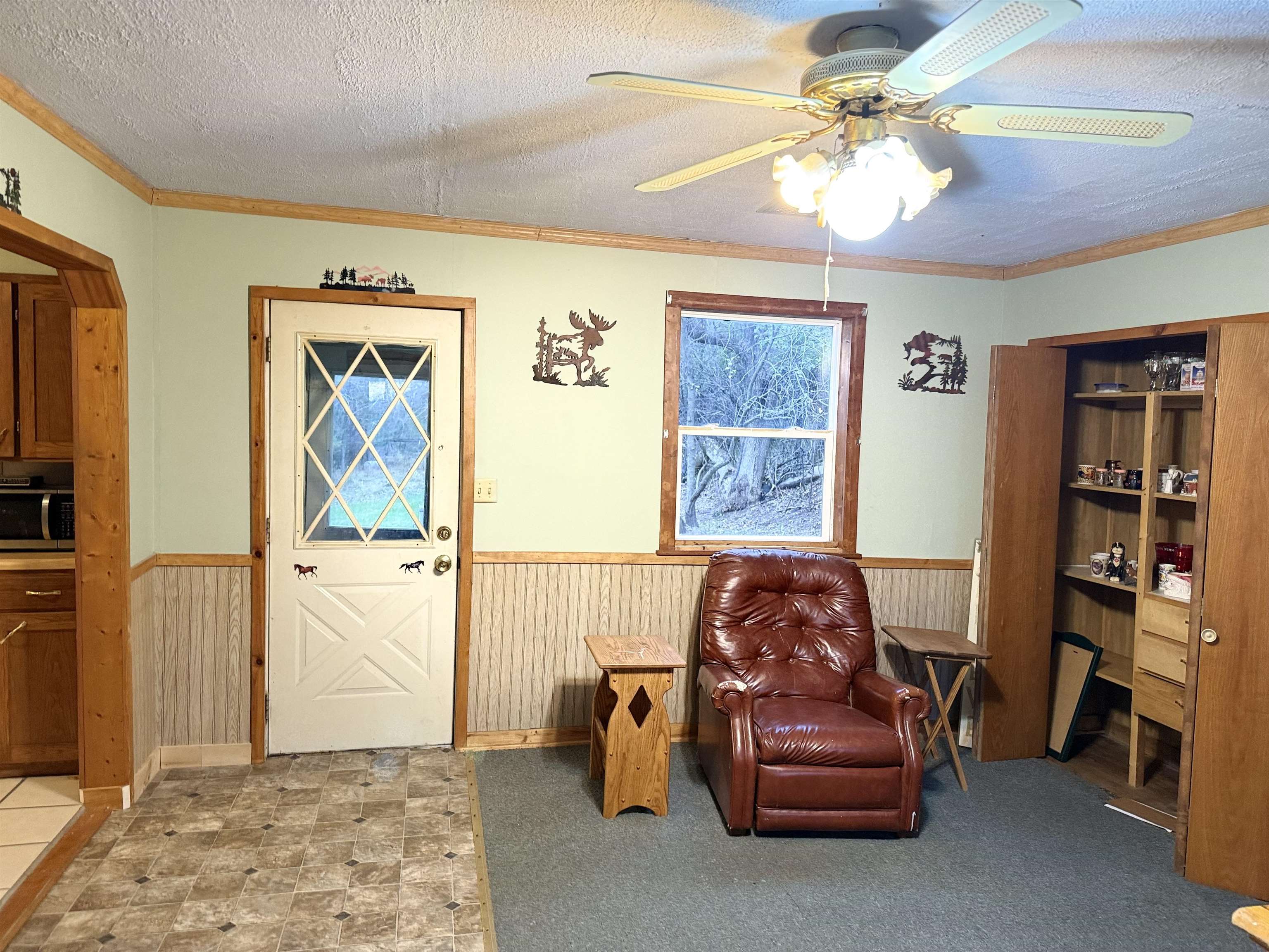 150 West 2nd Street Glidden, WI 54527 - Photo 15 of 32 Living area with a wainscoted wall, a textured ceiling, crown molding, a ceiling fan, and wood walls