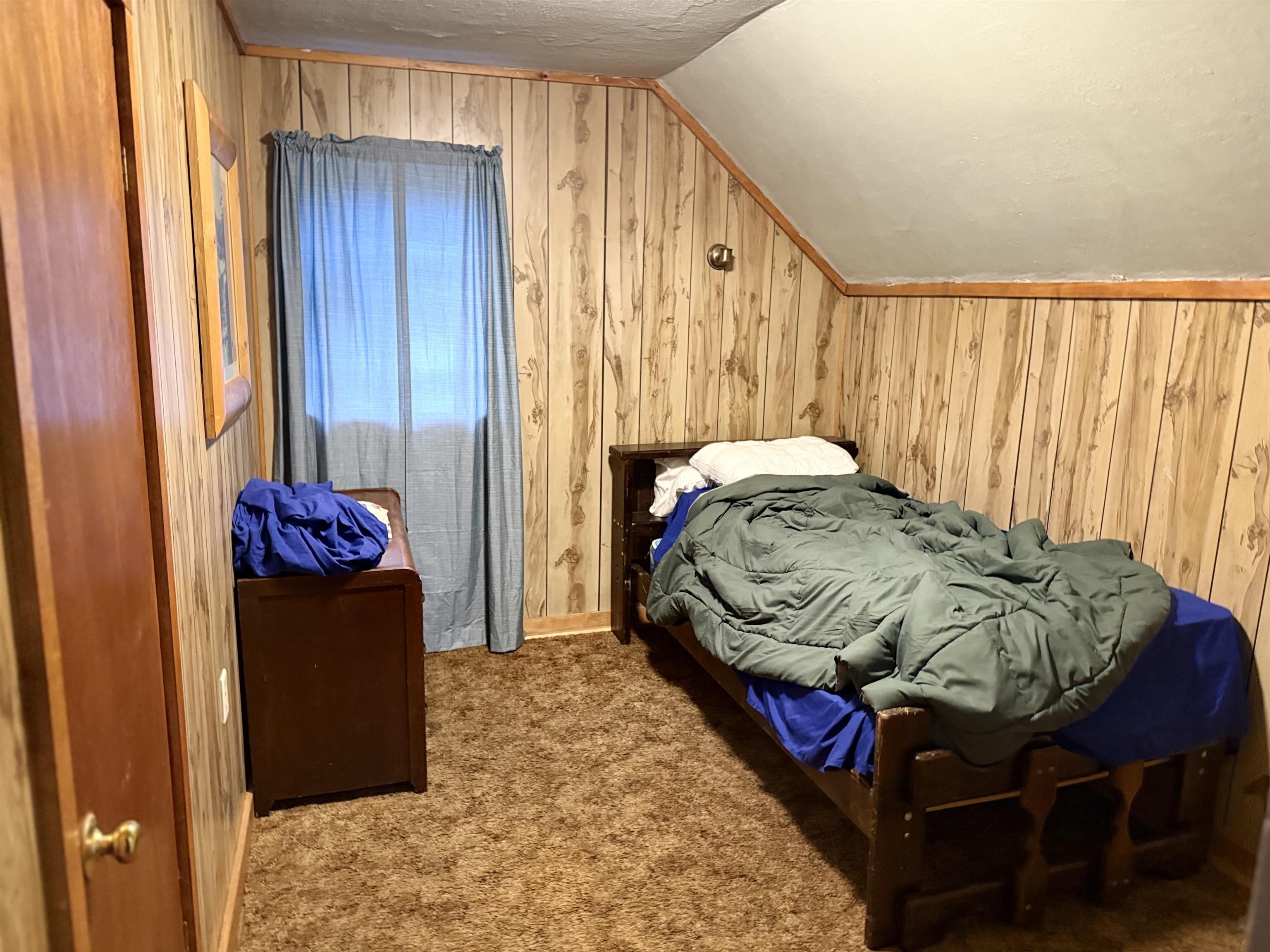 150 West 2nd Street Glidden, WI 54527 - Photo 21 of 32 Carpeted bedroom featuring wooden walls, vaulted ceiling, and a textured ceiling