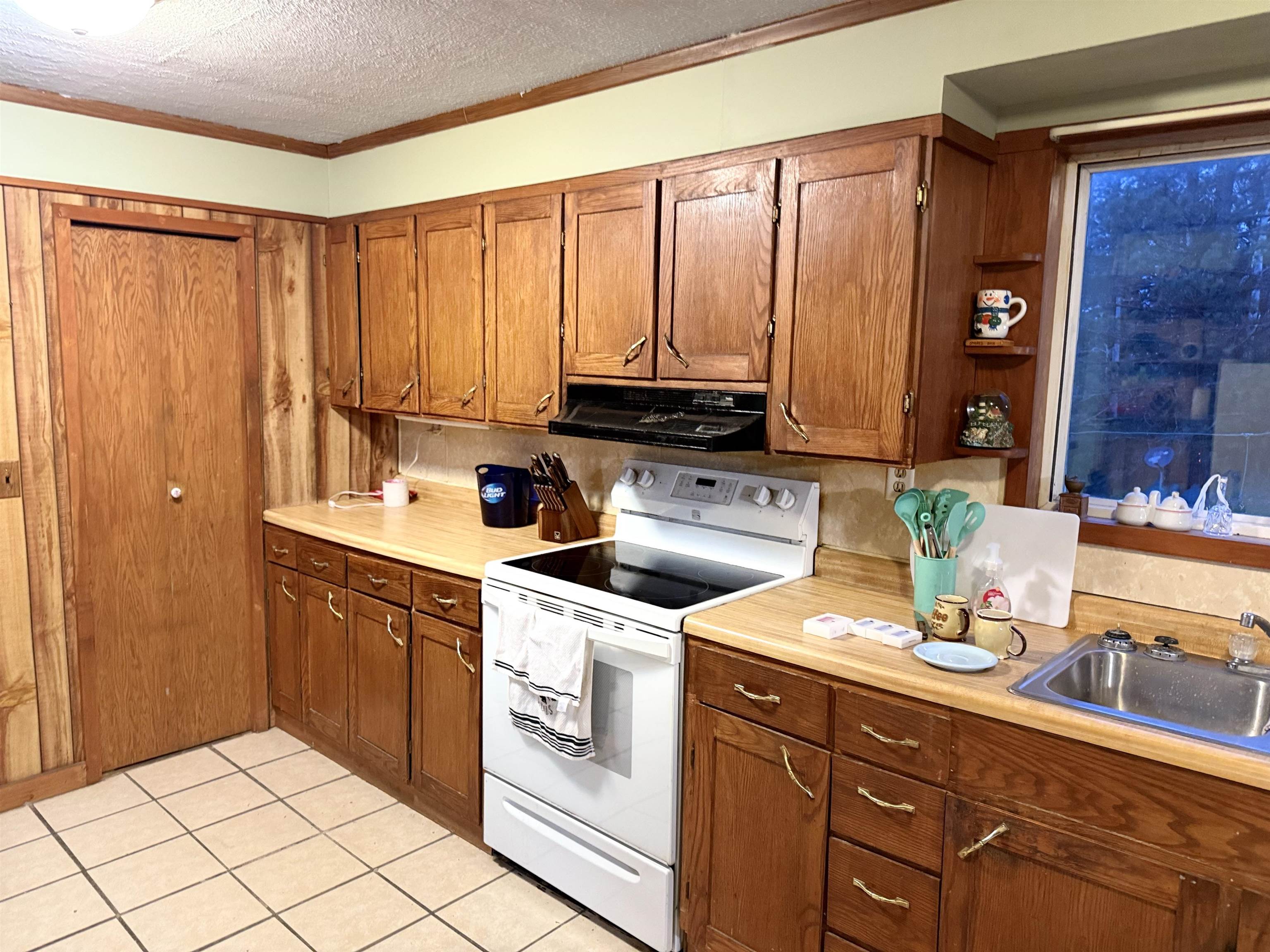 150 West 2nd Street Glidden, WI 54527 - Photo 8 of 32 Kitchen featuring white electric stove, light countertops, a textured ceiling, light tile patterned flooring, and crown molding