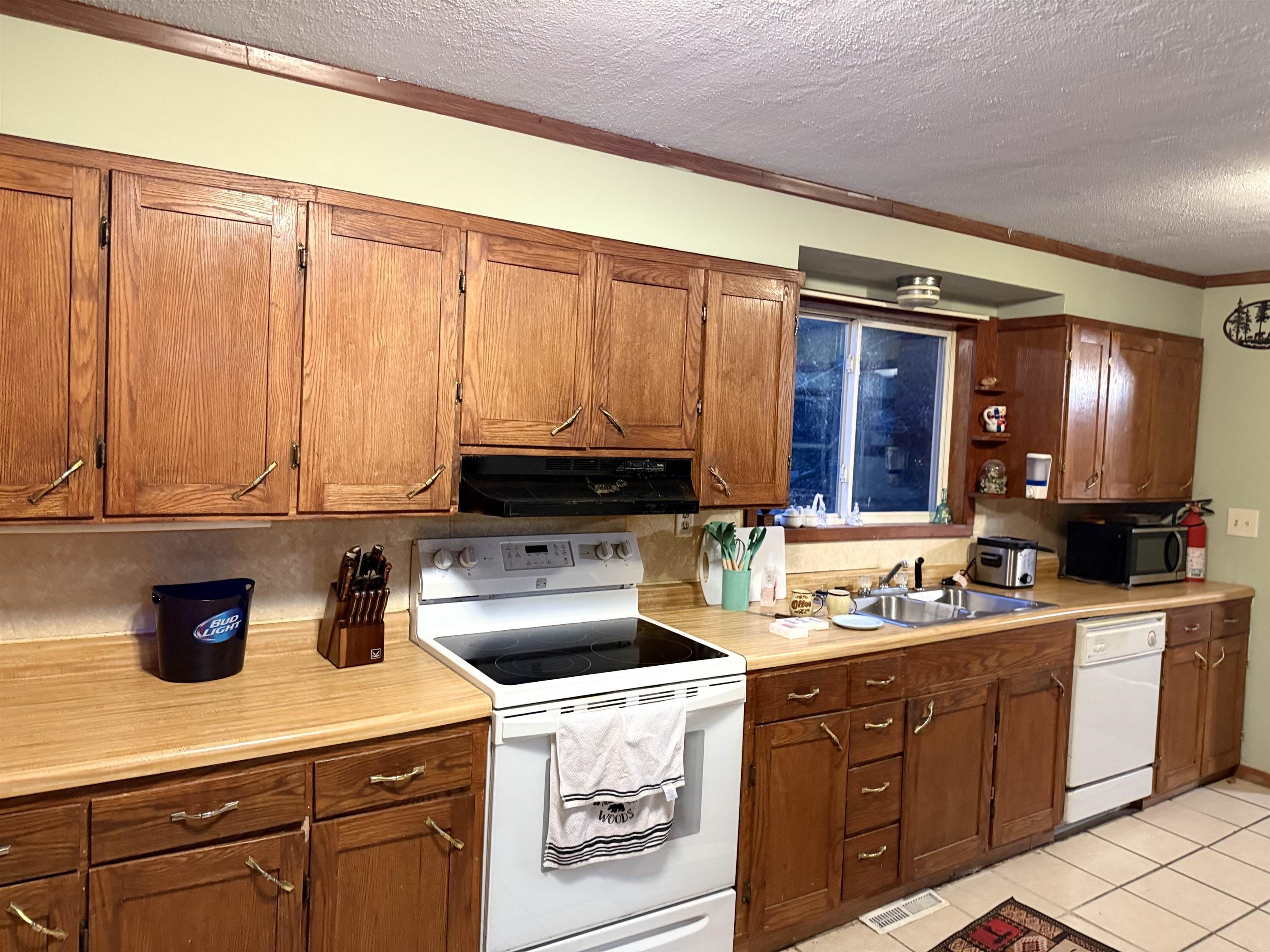 150 West 2nd Street Glidden, WI 54527 - Photo 9 of 32 Kitchen featuring white appliances, light countertops, a textured ceiling, crown molding, and light tile patterned floors