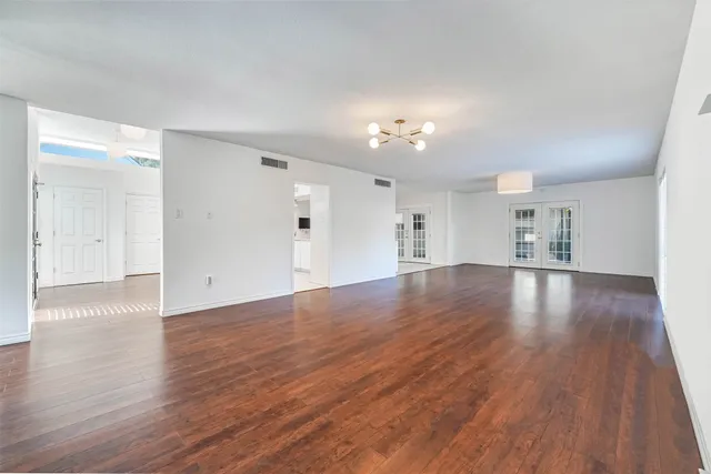 a view of empty room with wooden floor and kitchen
