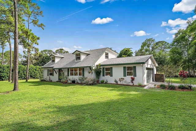 a front view of a house with a garden and trees