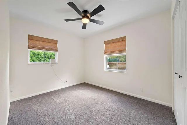 an empty room with a window and a ceiling fan