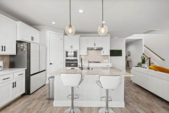a large kitchen with white cabinets and stainless steel appliances