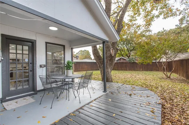 a view of a patio with a dining table and chairs with wooden floor and fence