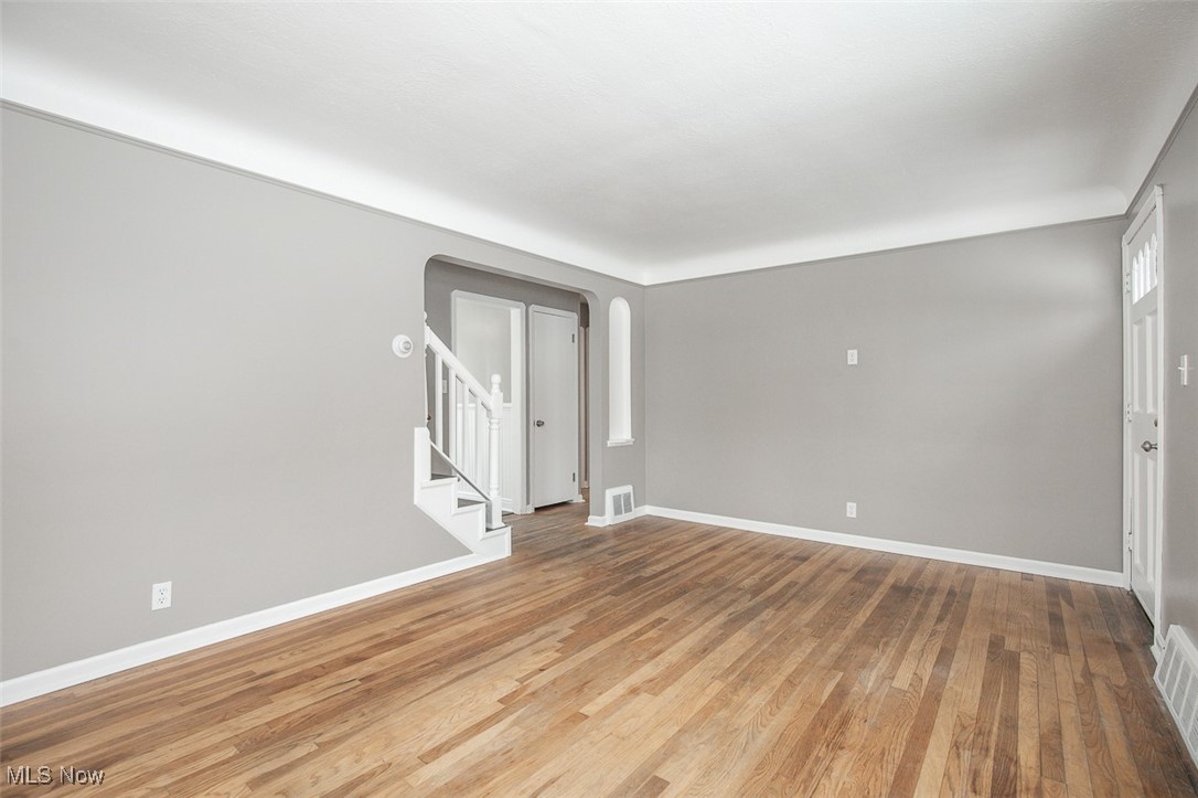 12328 Granger Road Cleveland, OH 44125 - Photo 7 of 37 Spare room featuring stairway, arched walkways, and light wood-style flooring