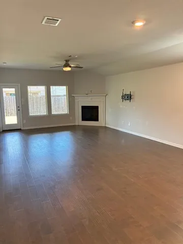 an empty room with wooden floor cabinet and windows