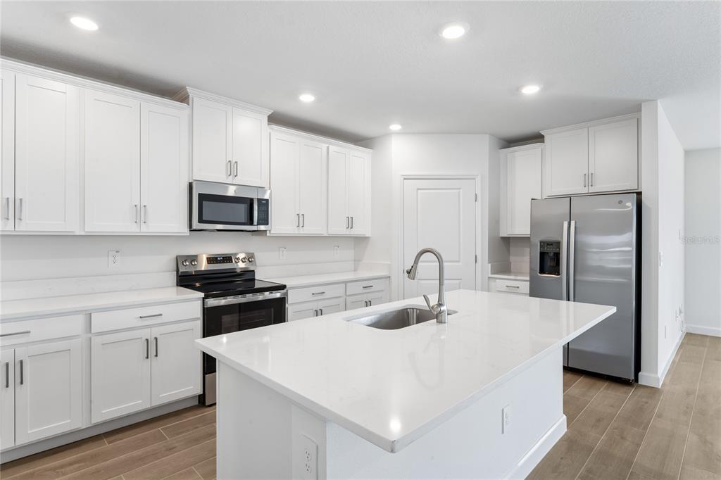 6692 Homebound Way New Port Richey, FL 34653 - Photo 13 of 47 a kitchen with kitchen island a white counter top space cabinets and stainless steel appliances
