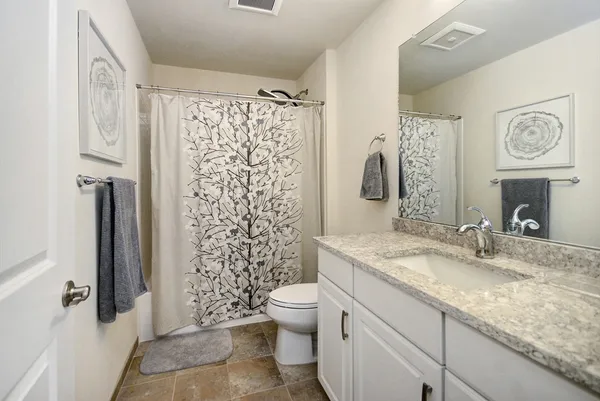 a bathroom with a granite countertop sink toilet and shower