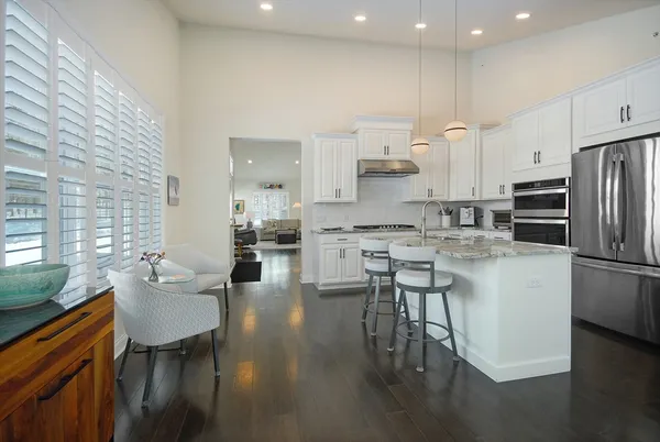 a kitchen with stainless steel appliances kitchen island granite countertop a dining table chairs refrigerator and sink