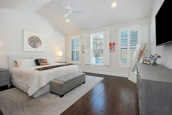 a bedroom with a large bed and a flat tv screen on dresser