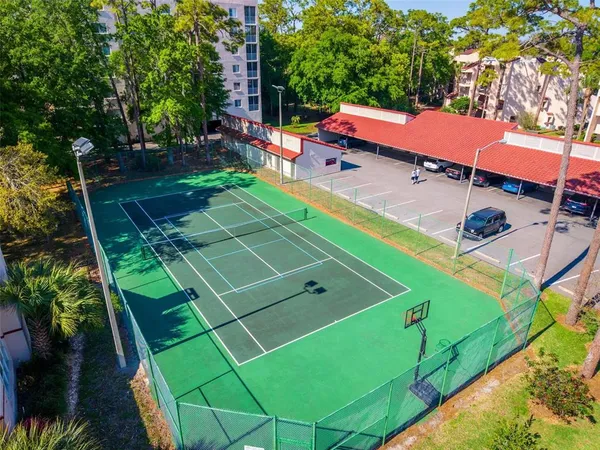 a view of a tennis ground with large trees