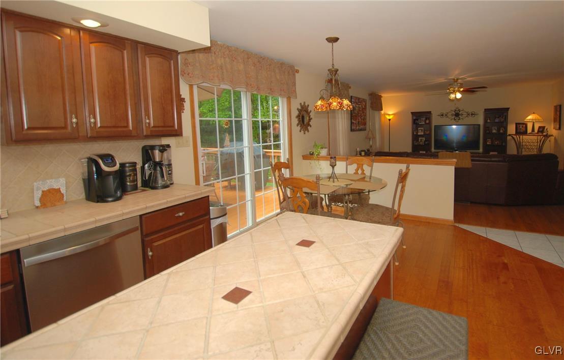 625 Turkey Ridge Road Mount Bethel, PA 18343 - Photo 12 of 43 a kitchen with stainless steel appliances kitchen island granite countertop a refrigerator a sink a dining table and chairs with wooden floor
