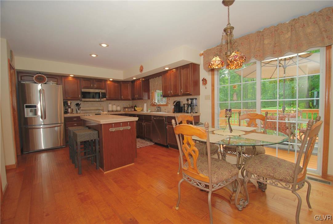 625 Turkey Ridge Road Mount Bethel, PA 18343 - Photo 14 of 43 a open kitchen with stainless steel appliances granite countertop a stove top oven a sink dishwasher a dining table and chairs with wooden floor
