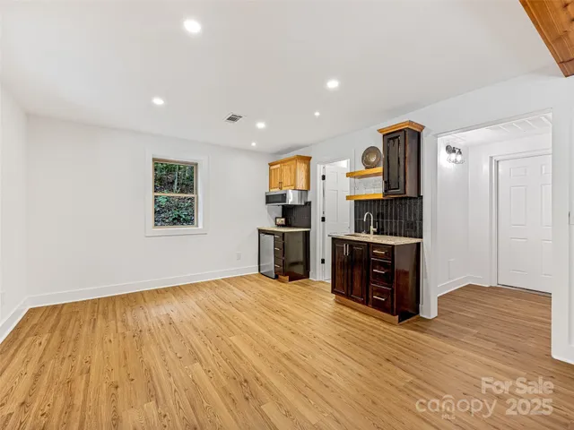 a view of a kitchen with wooden floor electronic appliances and windows