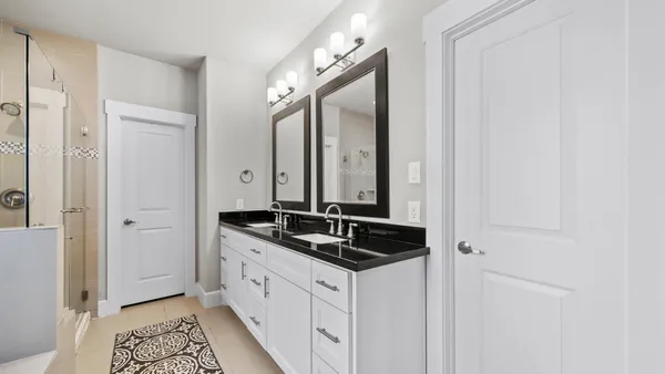a bathroom with a granite countertop double vanity sink a mirror and a bathtub