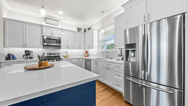 a kitchen with stainless steel appliances a stove a sink a refrigerator wooden floor and white cabinets