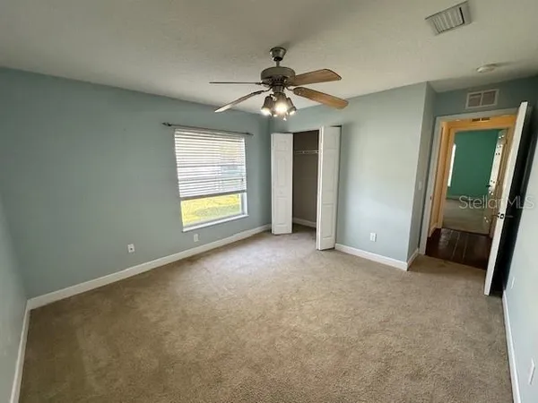 an empty room with chandelier fan and windows
