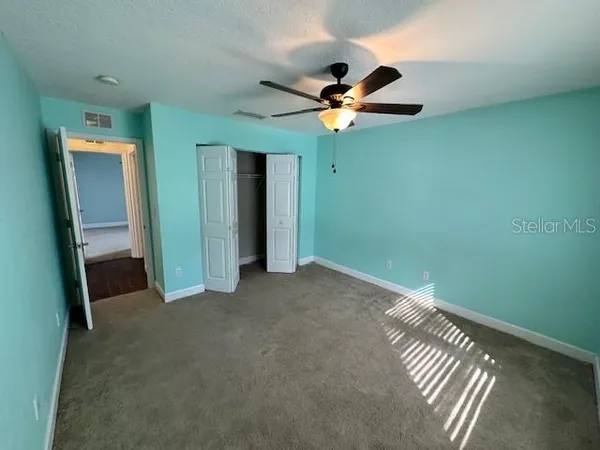 an empty room with closet and a chandelier fan