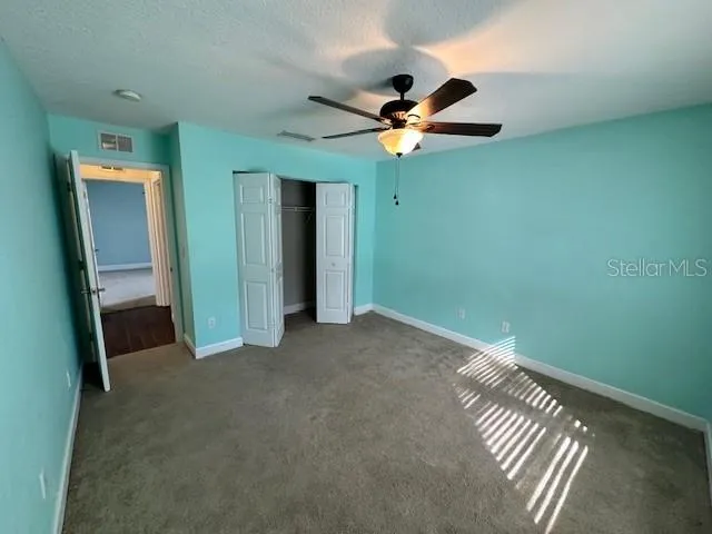 an empty room with closet and a chandelier fan