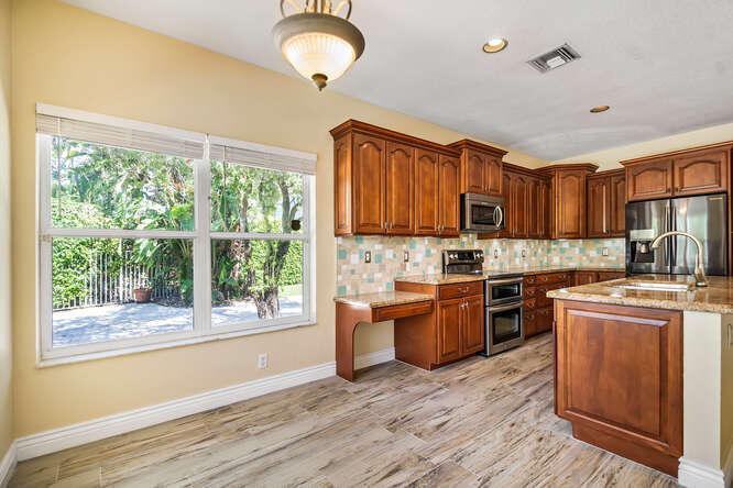 20933 La Plata Court Boca Raton, FL 33428 - Photo 15 of 60 a kitchen with stainless steel appliances granite countertop a stove top oven a sink dishwasher a refrigerator and a dining table with wooden floor