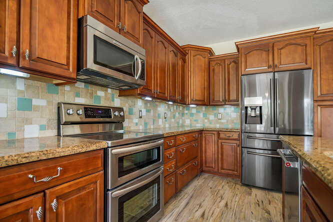 20933 La Plata Court Boca Raton, FL 33428 - Photo 19 of 60 a kitchen with stainless steel appliances granite countertop a refrigerator stove top oven and sink