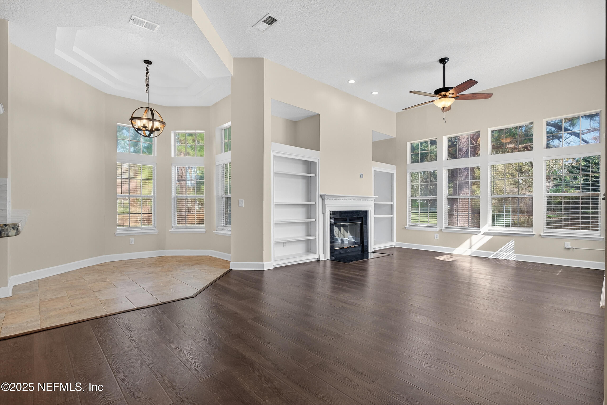 577 Hunters Grove Court Orange Park, FL 32073 - Photo 20 of 40 an empty room with wooden floor chandelier ceiling fan and windows