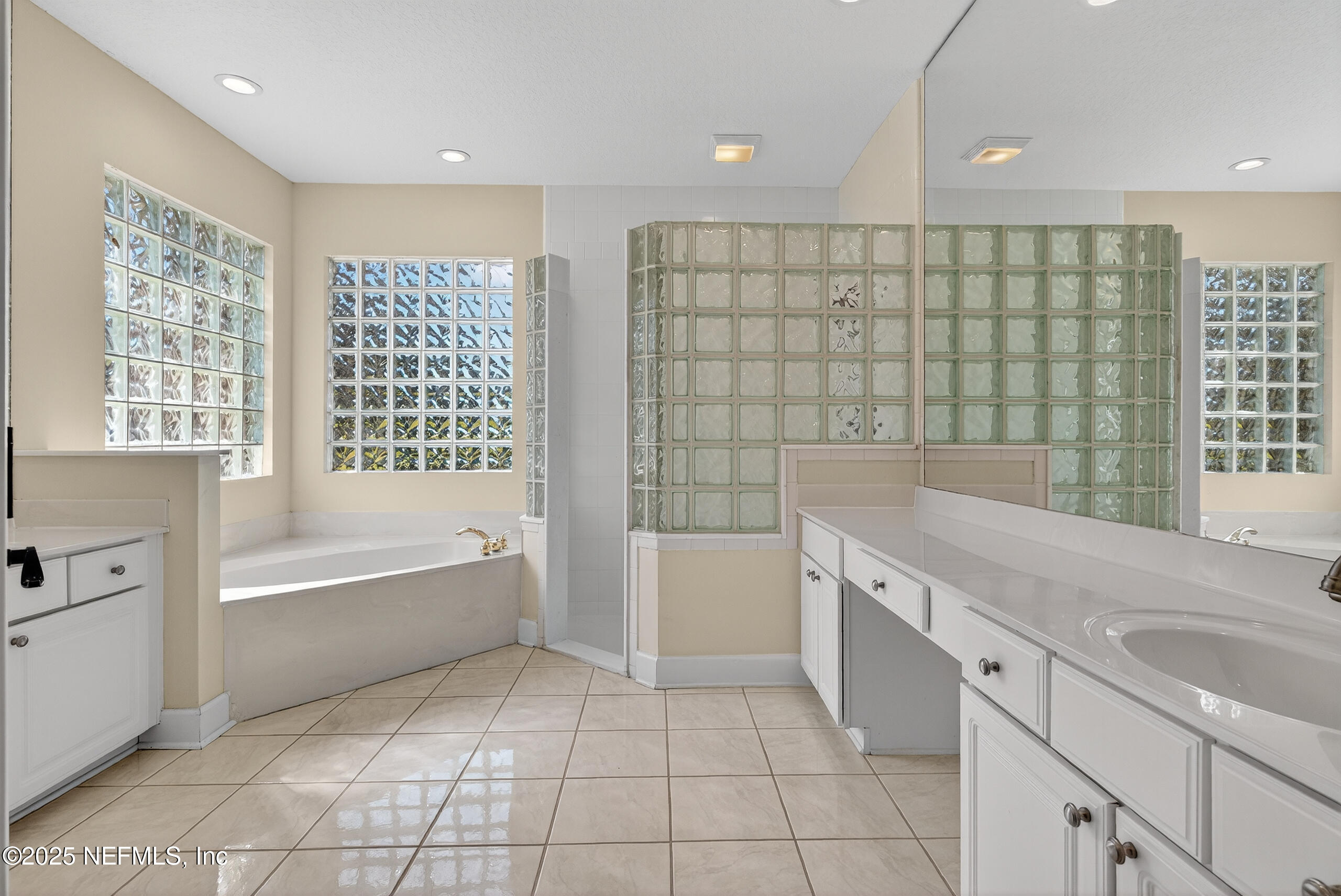 577 Hunters Grove Court Orange Park, FL 32073 - Photo 27 of 40 a spacious bathroom with a granite countertop sink a bathtub and next to a window