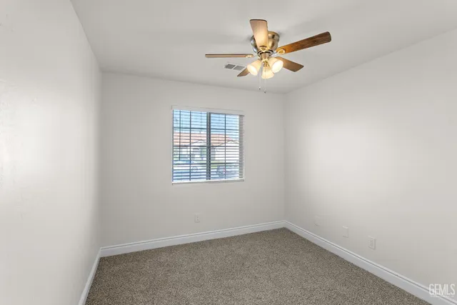 an empty room with chandelier fan and windows