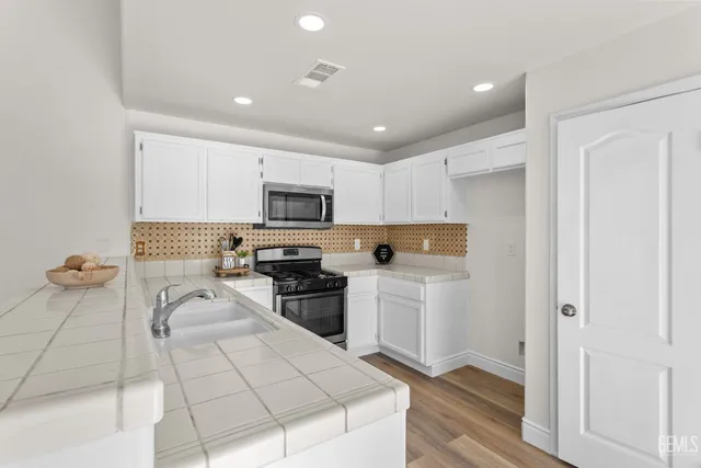 a kitchen with stainless steel appliances granite countertop a refrigerator and a stove top oven
