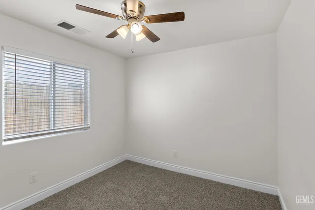 an empty room with a window and a fan