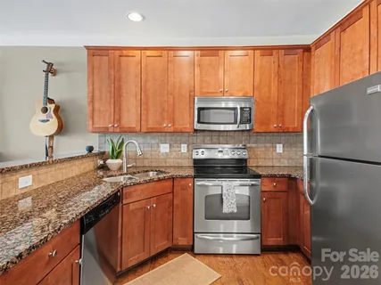 a kitchen with stainless steel appliances granite countertop a stove a sink dishwasher and a refrigerator