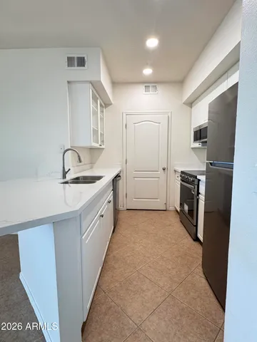 a large kitchen with a refrigerator a sink a stove and cabinets