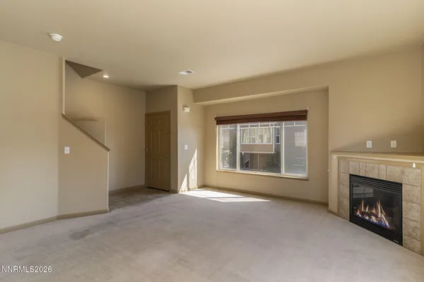 a view of an empty room with a window and fireplace