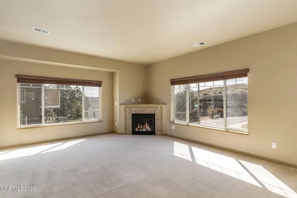 an empty room with a fireplace and large windows