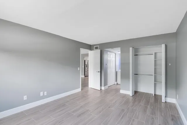 a view of an empty room with wooden floor and closet